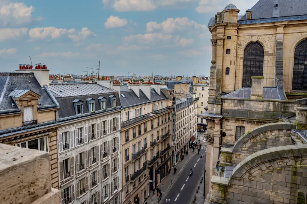 Vue sur les toits et la rue Saint-Sulpice depuis les hauteurs, avec le flanc de l'église en pierre
