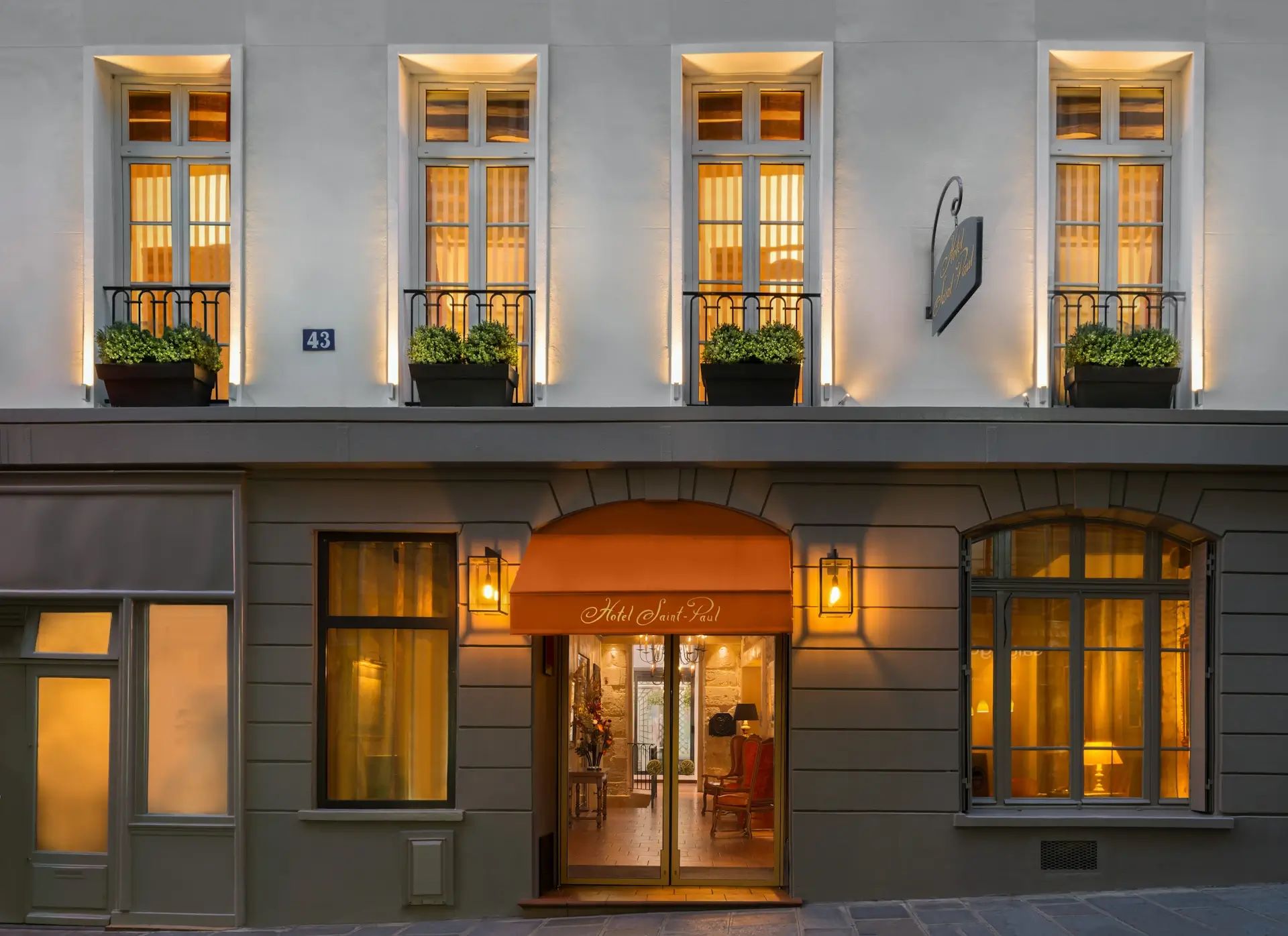 Façade de nuit de l'Hôtel Saint Paul Paris avec marquise d'entrée